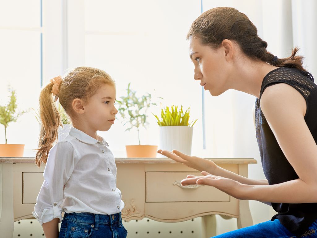 A calm caregiver setting boundaries with a young child during a moment of defiance