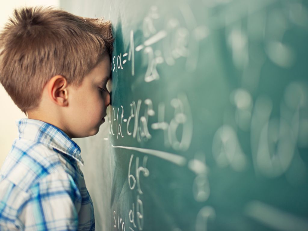 A young child concentrating while trying again at a challenging task with adult support

